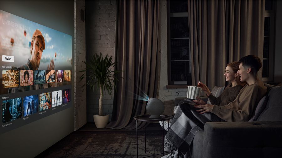 Projecteur BenQ GV50P en usage cinéma Projecteur portable BenQ GV50P projetant une interface de streaming sur un mur dans un salon sombre avec deux spectateurs.