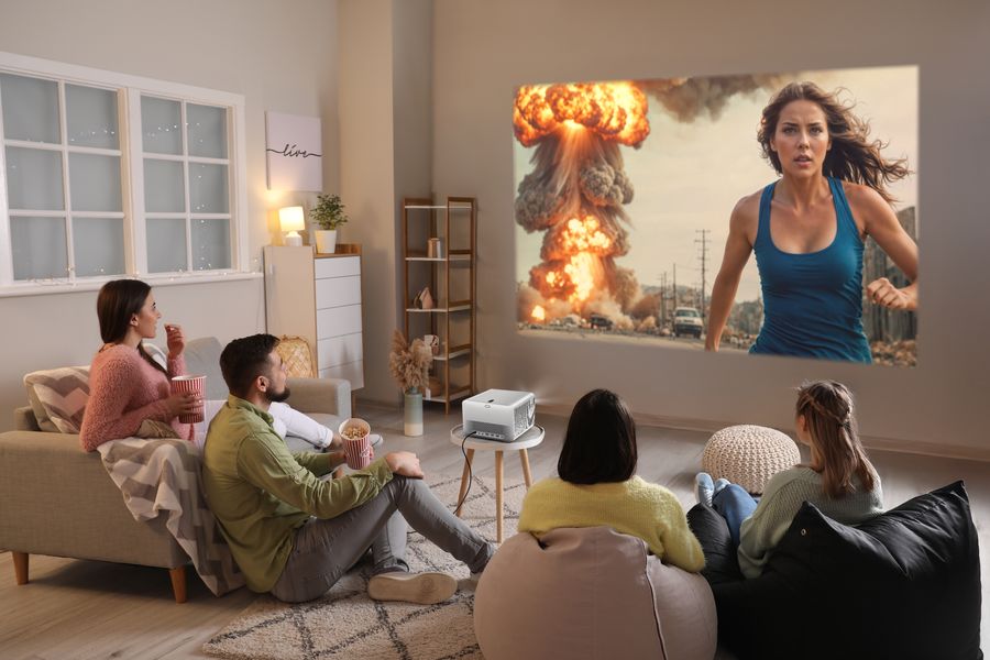 Quatre personnes regardent un film d’action projeté sur un mur avec un vidéoprojecteur 4K LED courte focale BenQ TK705STi.