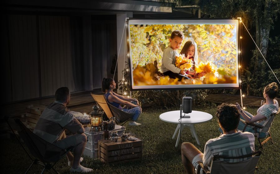 Une famille regarde un film dans le jardin grâce à un picoprojecteur
