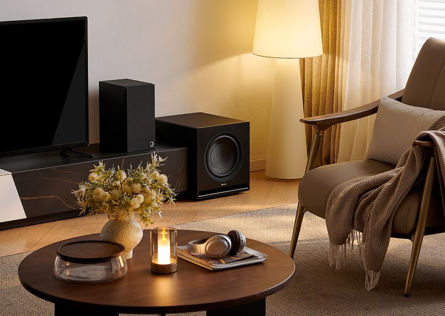 Caisson de basses Elipson Premium SUB 10 Caisson de basses Elipson Premium SUB 10 noir, installé dans un salon moderne à côté d'une enceinte et d'un téléviseur.