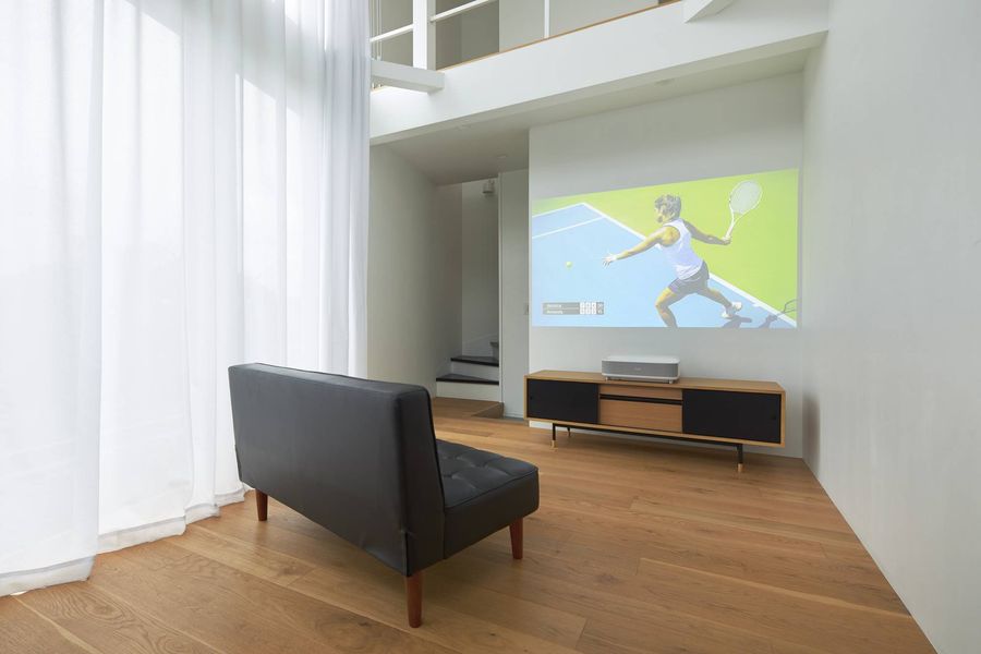 Projecteur ultra-courte focale Epson EH-LS670 affichant une image lumineuse sur un mur dans un salon moderne.