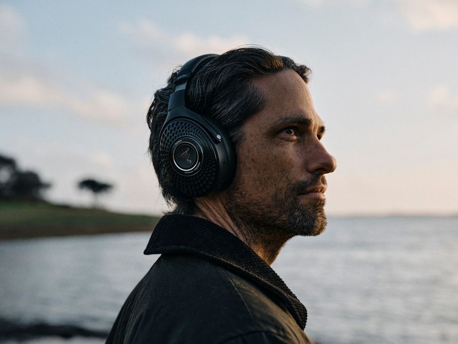 Un homme porte le casque Bluetooth Focal Bathys en contemplant un paysage au bord de l’eau.