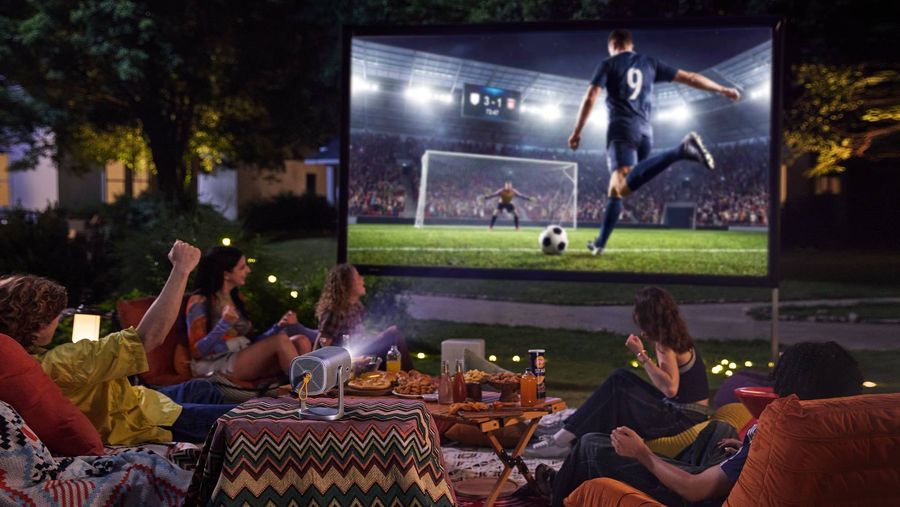 Vid&eacute;oprojecteur portable Hisense P1 projetant un match de football sur grand &eacute;cran lors d'une soir&eacute;e entre amis en ext&eacute;rieur.