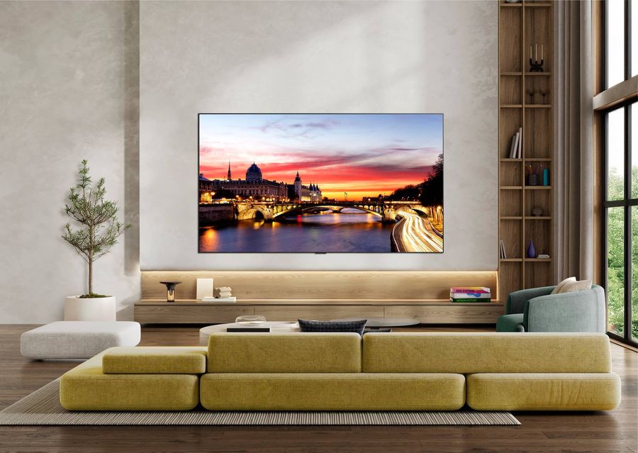 T&eacute;l&eacute;viseur LG OLED77C6 fix&eacute; au mur dans un salon spacieux diffuse un paysage urbain au cr&eacute;puscule avec couleurs intenses et contraste pr&eacute;cis.