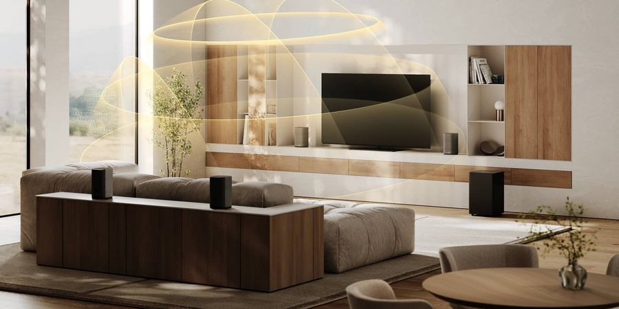 Syst&egrave;me home cin&eacute;ma sans fil Loewe We. BOOST compos&eacute; de quatre enceintes satellites et d&rsquo;un caisson de basses dans un salon contemporain.