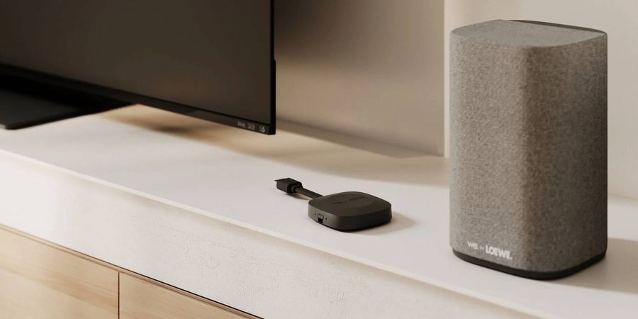 Dongle HDMI eARC et enceinte satellite du syst&egrave;me home cin&eacute;ma sans fil Loewe We. BOOST install&eacute;s &agrave; proximit&eacute; d&rsquo;un t&eacute;l&eacute;viseur.