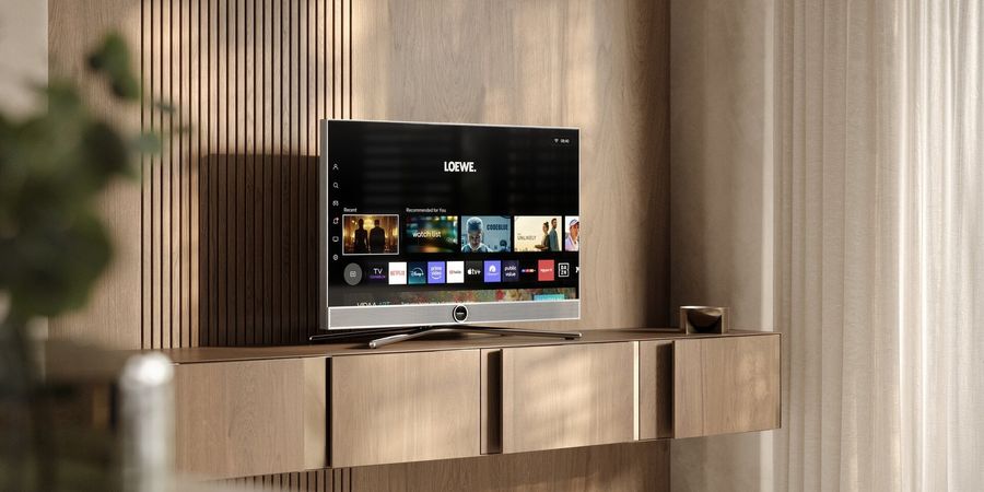 T&eacute;l&eacute;viseur UHD 4K Loewe VEGA 43 pos&eacute; sur un meuble bois, affichant interface connect&eacute;e dans un salon lumineux moderne