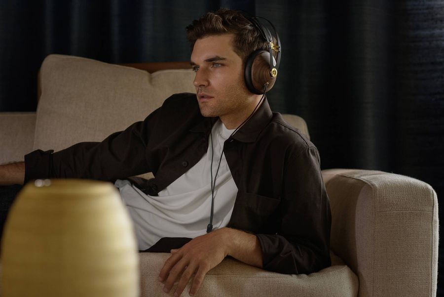 Casque hi-fi Meze 99 Classics V2 Un homme détendu sur un canapé porte le casque hi-fi Meze 99 Classics V2 avec coques en bois foncé.