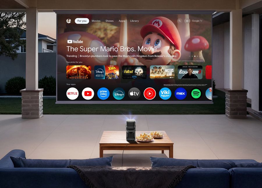 Projecteur Nebula P1 affichant l'interface Google TV sur grand &eacute;cran dans un espace ext&eacute;rieur couvert.