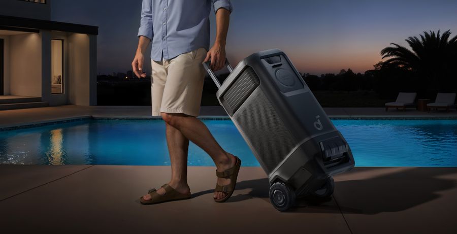 Un homme transporte facilement le projecteur Nebula X1 Pro &agrave; roulettes pr&egrave;s d&rsquo;une piscine au coucher du soleil.