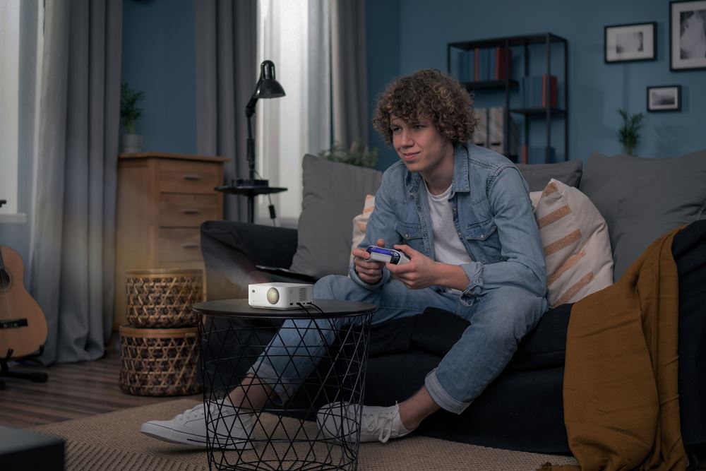 Vidéoprojecteur Optoma ML1080 compact et portable, projetant une image pendant une session de jeu vidéo sur canapé.