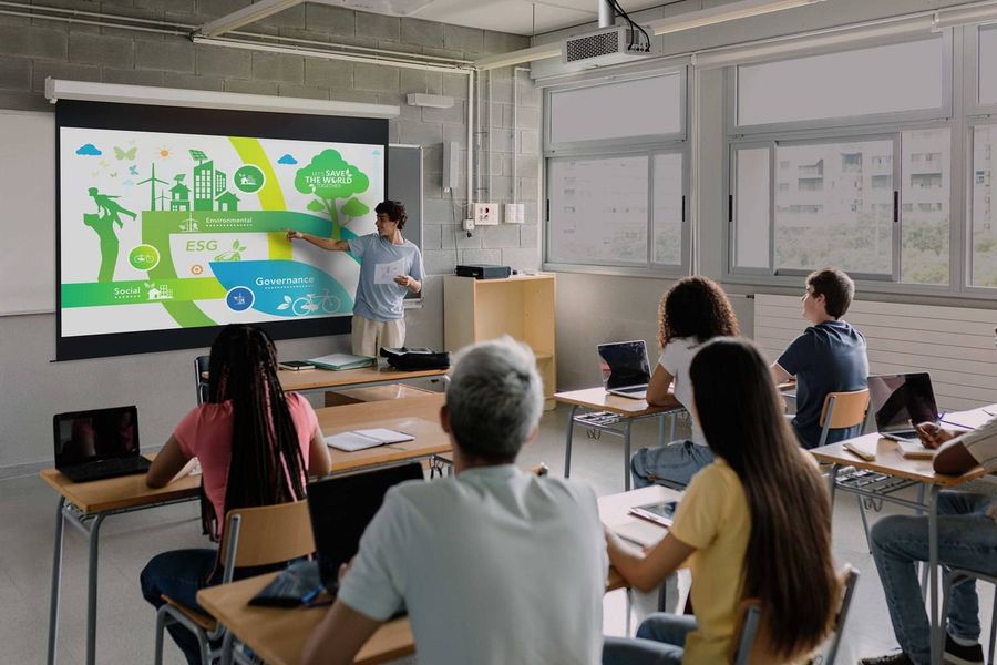 Vid&eacute;oprojecteur Optoma ZH551 install&eacute; au plafond d&rsquo;une salle de classe et projetant un support p&eacute;dagogique sur grand &eacute;cran.
