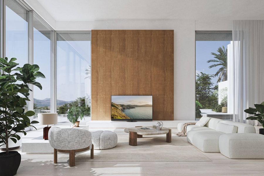  Téléviseur OLED Panasonic TV-55Z95B installé dans un salon lumineux et moderne, affichant un paysage côtier détaillé.