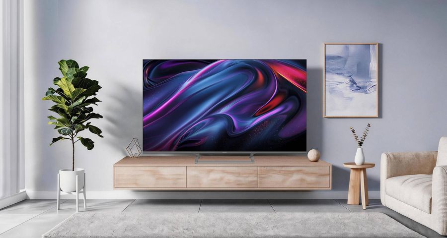 T&eacute;l&eacute;viseur QLED 4K Panasonic TV-65W83C de 164 cm pr&eacute;sent&eacute; de face sur un meuble en bois dans un salon lumineux.