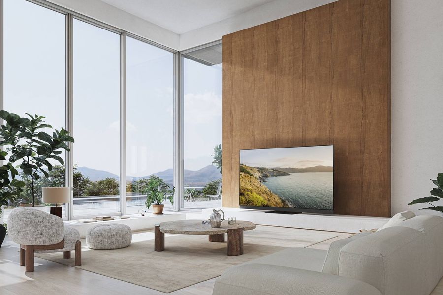  Téléviseur OLED Panasonic TV-77Z95B installé dans un salon moderne, affichant une image de paysage côtier.