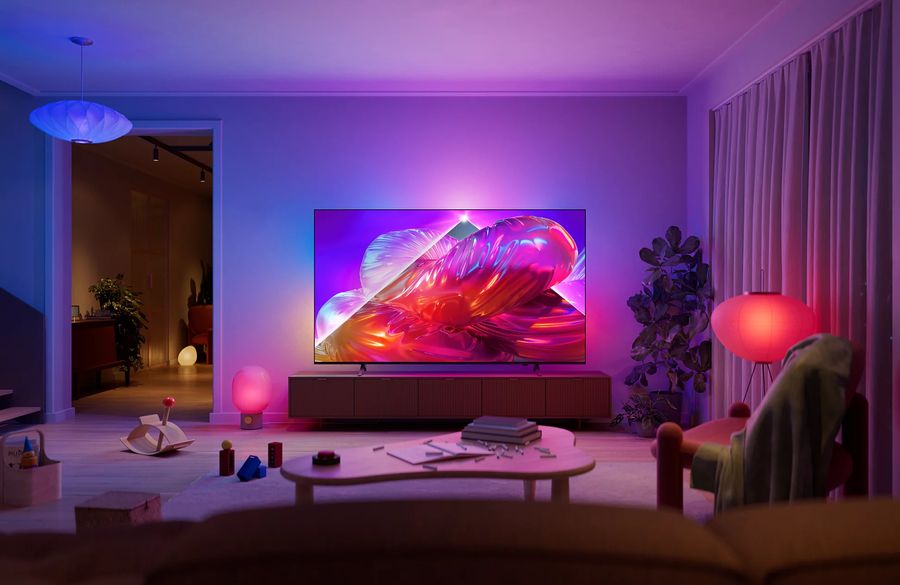 TV Philips 100PQS9001 The One affichant une image color&eacute;e dans un salon &eacute;clair&eacute; par une ambiance lumineuse coordonn&eacute;e.