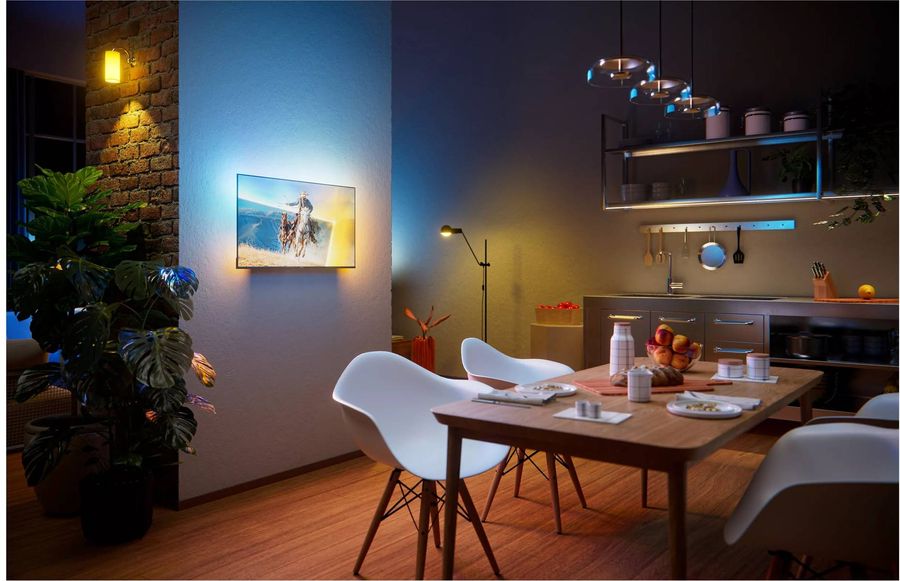 TV QLED Full HD 40" Philips 40PQS6901 avec Ambilight install&eacute;e dans une cuisine ouverte, diffusant une image lumineuse sur un mur.