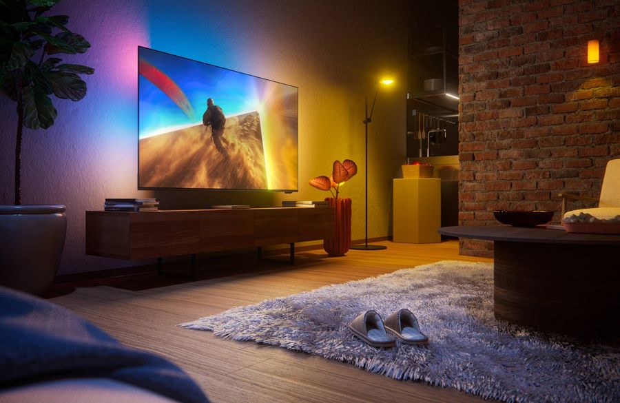 T&eacute;l&eacute;viseur QLED 4K Philips 50PQS8701 avec Ambilight 3 c&ocirc;t&eacute;s install&eacute; dans un salon moderne &agrave; l'ambiance lumineuse immersive.