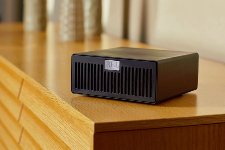 &Eacute;metteur sans fil REL Acoustics AirShip II pour caisson de basses, pos&eacute; sur un meuble en bois clair.