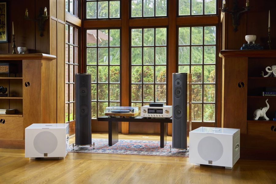 Deux caissons de basses REL Acoustics S/850 blancs sont positionnés dans un salon décoré de boiseries avec un système hi-fi.