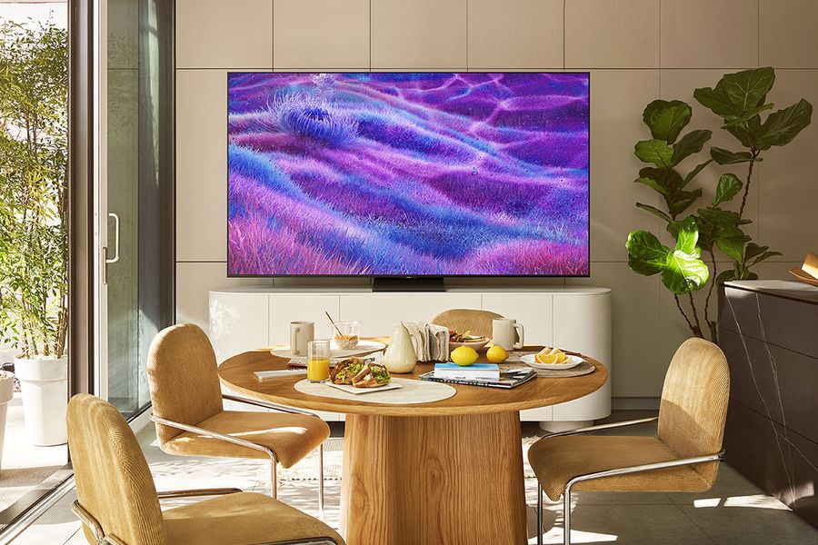  Téléviseur Mini LED 4K Samsung TQ100QN80F accroché au mur d'une salle à manger moderne et bien éclairée.