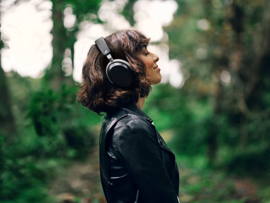 Femme portant un casque Bluetooth Sennheiser HDB 630 noir, en pleine nature, profitant d’un moment d’écoute.