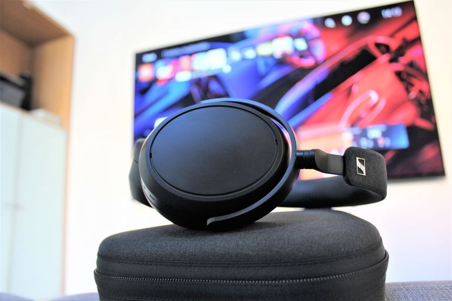 Voir le casque Bluetooth Sennheiser Momentum 4 Casque Bluetooth Sennheiser Momentum 4 avec TV en arrière plan