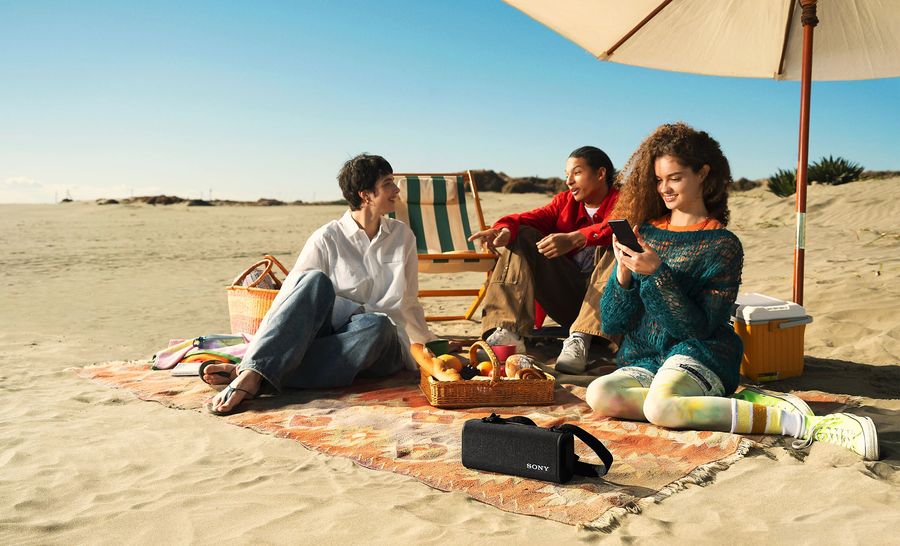 Enceinte Sony ULT Field 3 à la plage avec un groupe d'amis