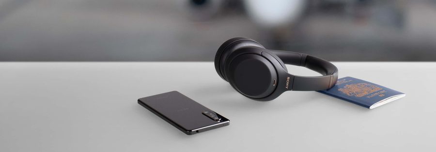 Mise en situation Sony WH1000XM4 Noir avec smartphone et passeport Mise en situation Sony WH1000XM4 Noir
