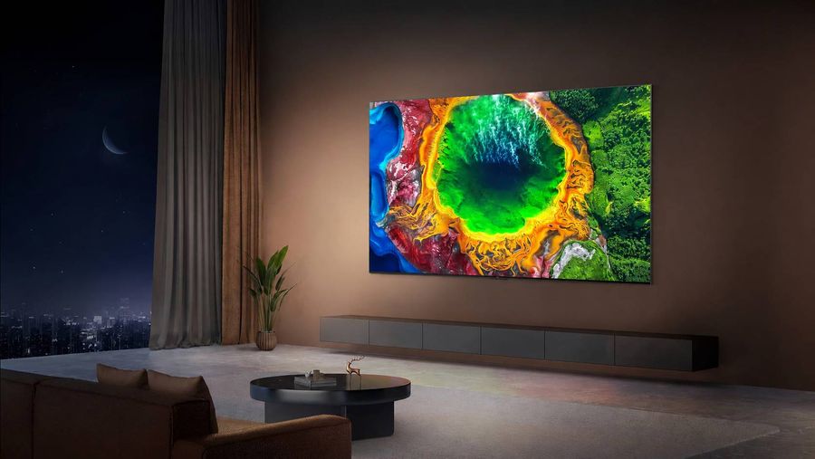 T&eacute;l&eacute;viseur RGB Mini LED TCL 85RM7L install&eacute; dans un salon moderne, affichant une image aux couleurs vives sur un grand &eacute;cran mural.
