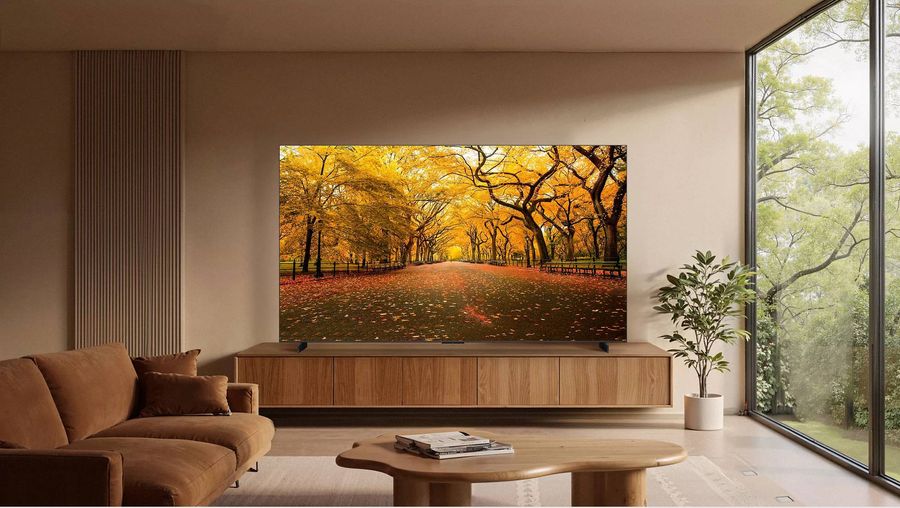 T&eacute;l&eacute;viseur Mini LED 4K TCL 98C8L install&eacute; dans un salon contemporain, affichant une all&eacute;e bord&eacute;e d&rsquo;arbres aux couleurs automnales.