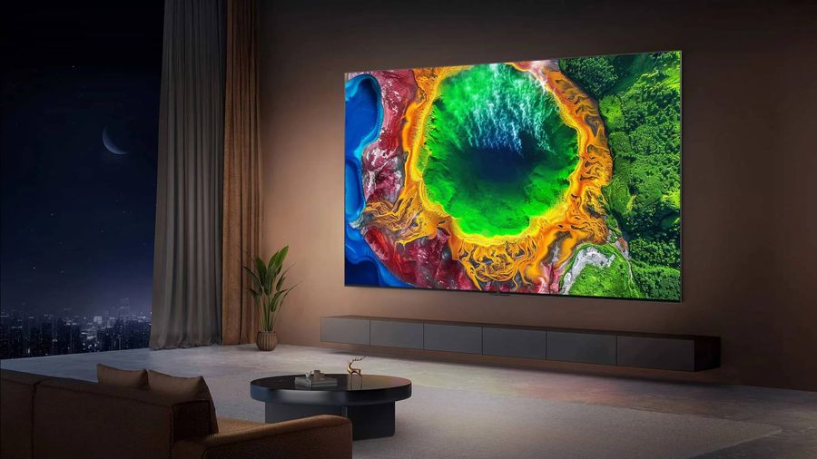T&eacute;l&eacute;viseur RGB Mini LED TCL 98RM7L install&eacute; dans un salon moderne, affichant une image lumineuse et color&eacute;e sur un tr&egrave;s grand &eacute;cran mural.