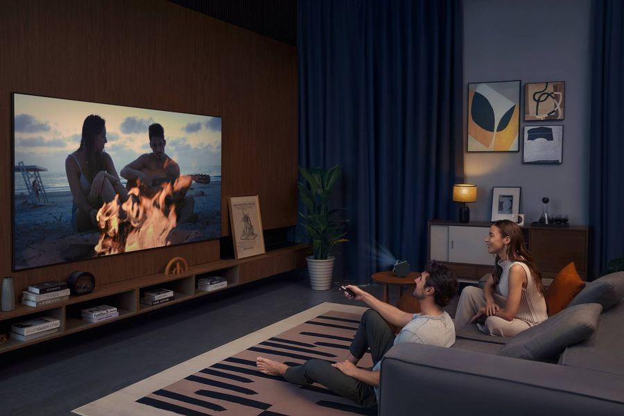 Projecteur compact TCL PlayCube Full HD 1080p diffusant un film dans un salon moderne &agrave; l&rsquo;ambiance tamis&eacute;e et confortable.