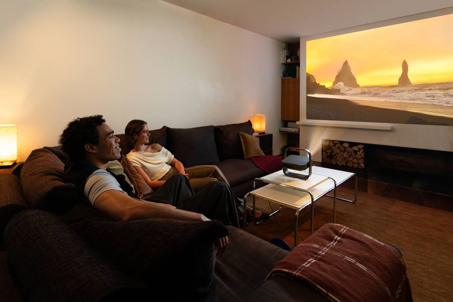 Projecteur Xgimi Elfin Flip 4K projetant une grande image dans un salon, avec deux personnes profitant d'une s&eacute;ance de visionnage.