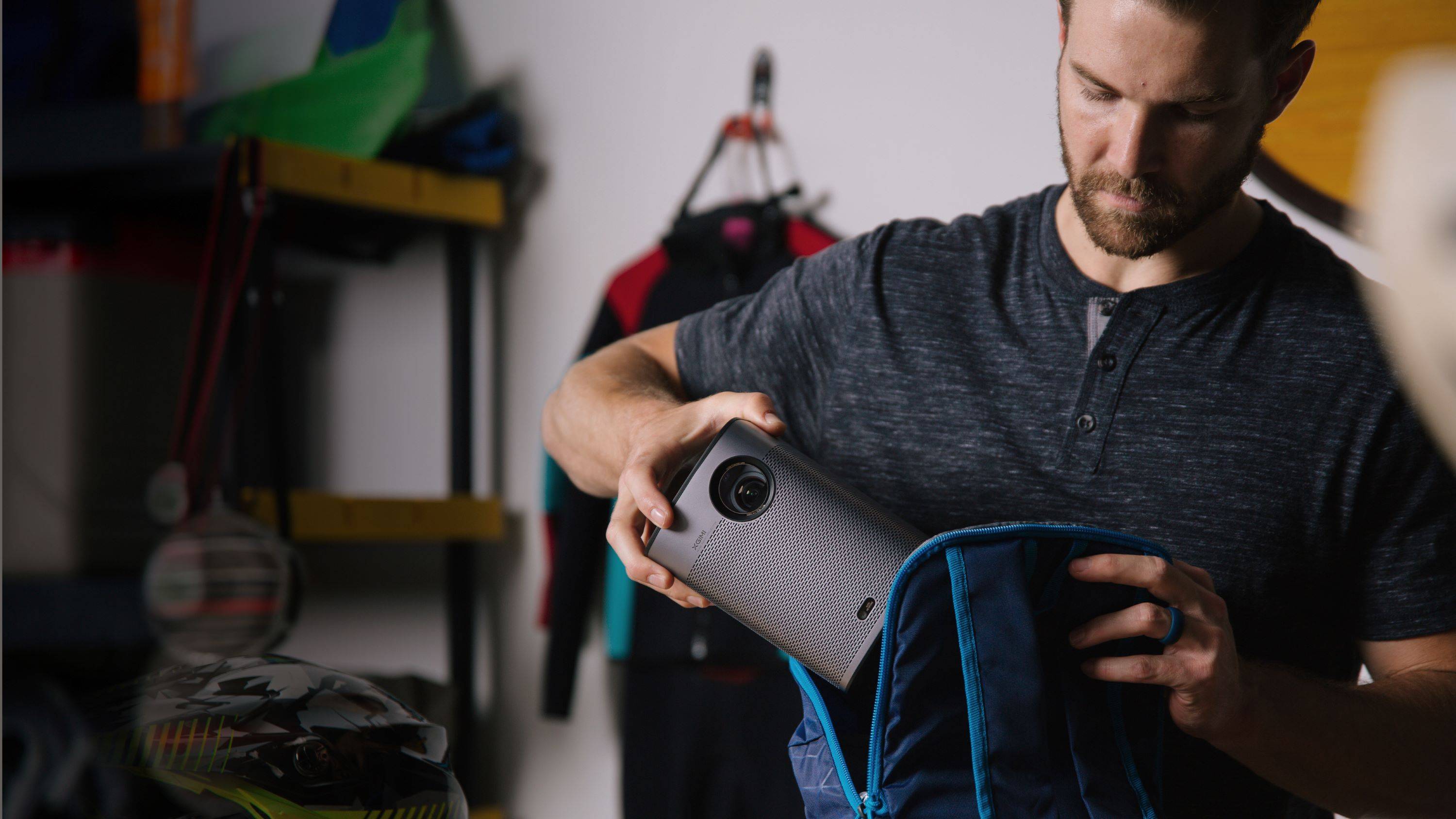 Un homme range le vidéoprojecteur portable XGIMI Halo+ Google TV Full HD dans son sac à dos.