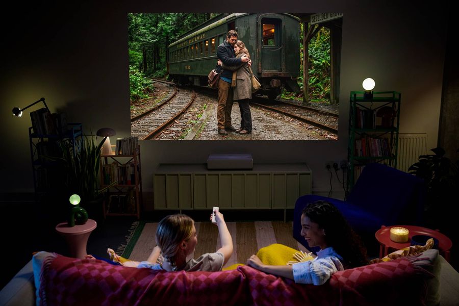 Vid&eacute;oprojecteur 4K ultra courte focale XGIMI MIRA Pro diffusant un film en grand format dans un salon sombre.