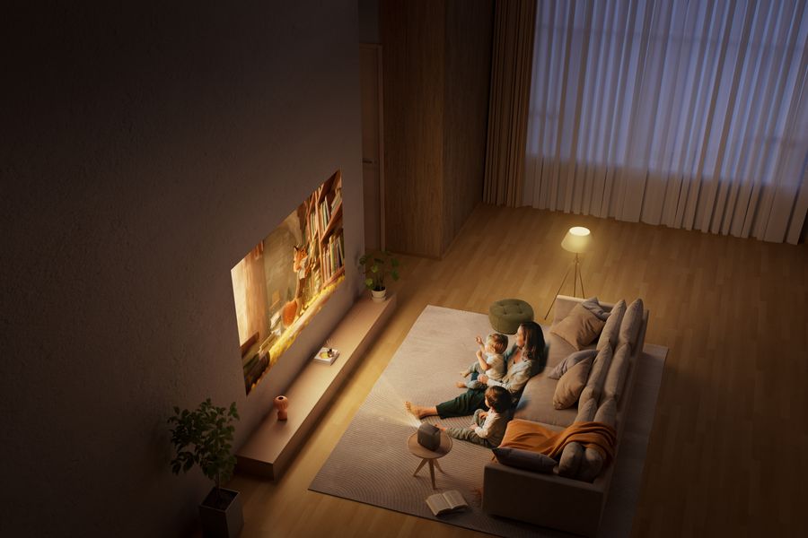 Une famille regarde un dessin animé projeté au mur par le mini projecteur Xming Page Two, compact et Full HD.